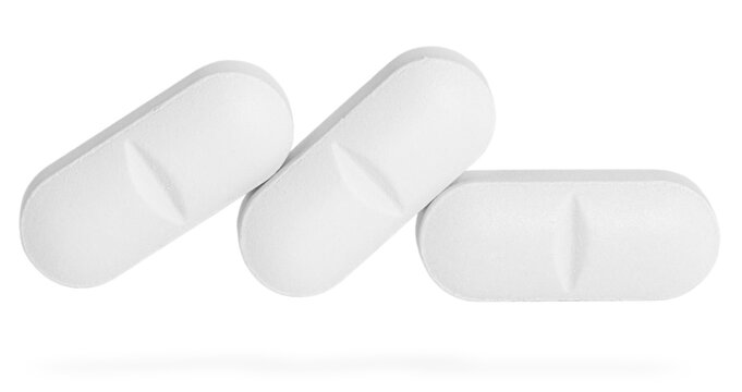 Different pills in row isolated on white. White medicine tablet, clearly depicting shape and the distinct central score line for easy division.