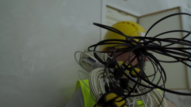 Angry senior construction worker throwing a tangled bundle of electrical wires towards the camera