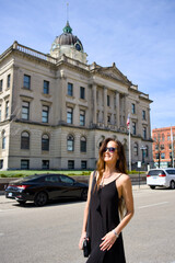Fototapeta premium Woman in Black Dress Standing Near Historic Courthouse Building
