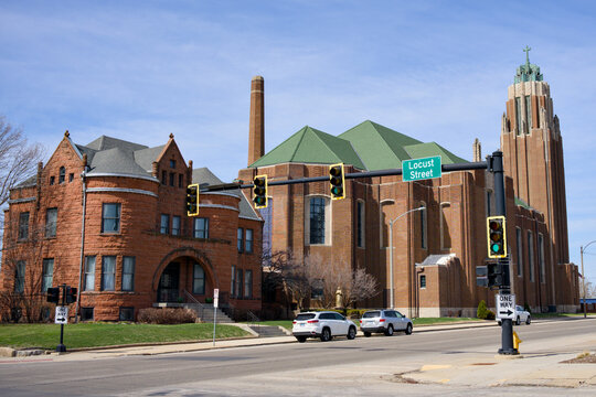 Large historic red brick church with green copper roof corner tower and traffic signal blue sky