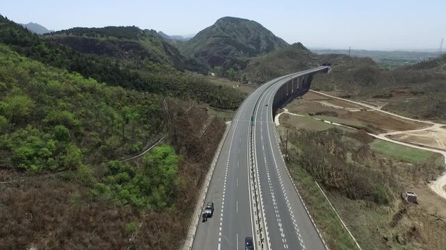 Aerial view of expressway curving along mountainside with railway nearby