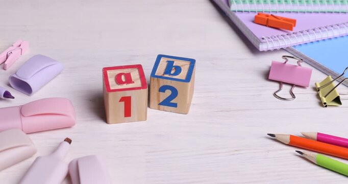 Woman putting cubes with letters and numbers on white wooden table, closeup