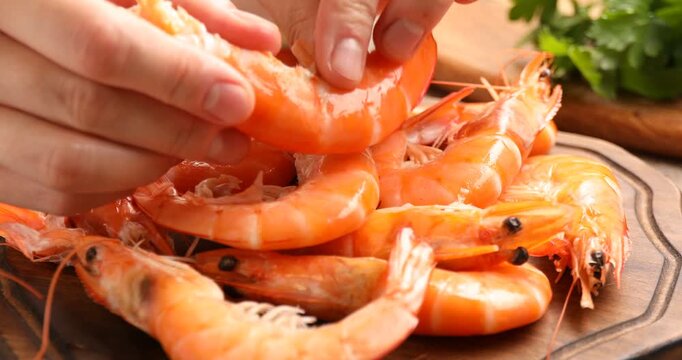 Woman peeling freshly cooked shrimp at table, closeup
