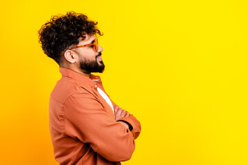 Confident young man with glasses smiling in profile against a vibrant yellow background, casual portrait conveying happiness, style and modern lifestyle © deagreez