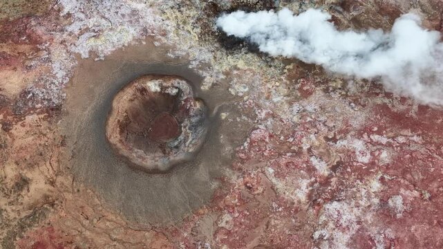 Aerial view of volcanic crater emitting steam with rugged lava fields in Reykjanesbaer, Iceland.