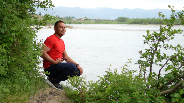 A man is traveling in the Altai Mountains. He enjoys the views of the Katun River and takes a photo of the confluence of the two rivers. The confluence of the Chuya and Katun rivers.