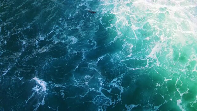 Aerial view of ocean waves crashing with white foam and turquoise water in Scotland, United Kingdom.