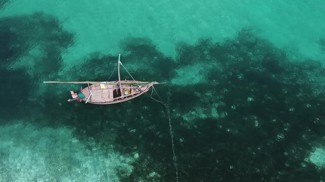 Aerial view of a traditional wooden dhoni boat floating in clear turquoise water in Vaikaradhoo, Haa Dhaalu Atoll, Maldives.