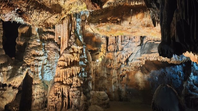 Illuminated Limestone Cave Interior with Stalactites and Stalagmites