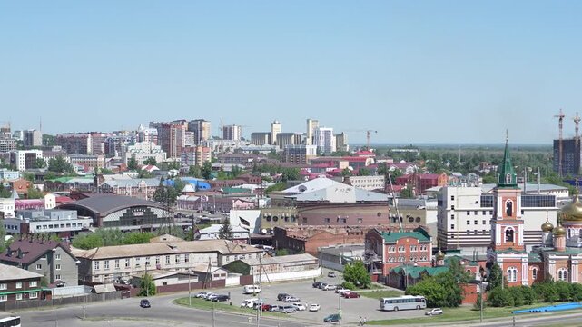 A cinematic high-angle panoramic video panning left across the urban cityscape of Barnaul city under a clear blue sky.