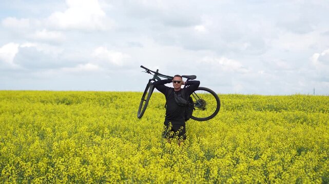 Moments of cycling. A man poses with his bicycle in a rapeseed field; a male athlete holds his bicycle behind his head, enjoying the views of the yellow rapeseed field.