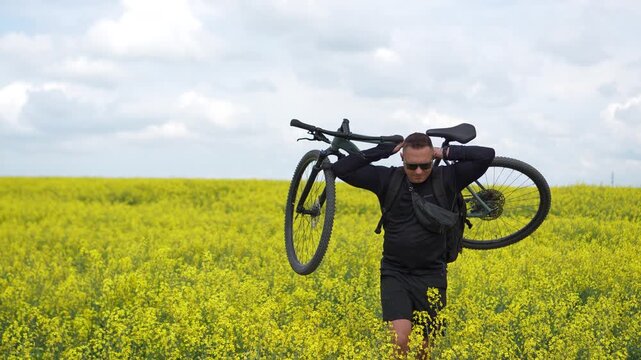 Moments of cycling. A man poses with his bicycle in a rapeseed field; a male athlete holds his bicycle behind his head, enjoying the views of the yellow rapeseed field.