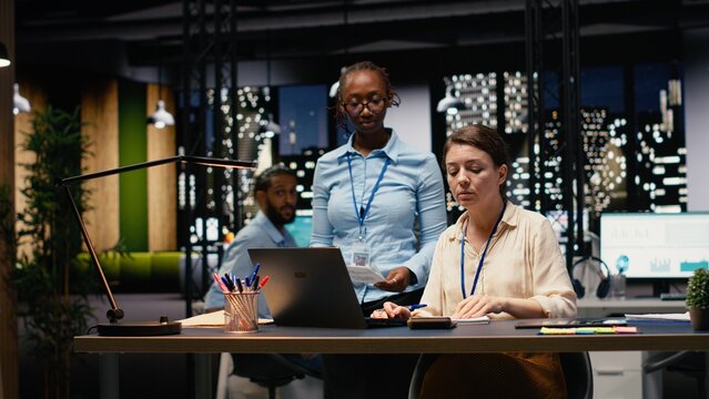 Diverse man and women working together on project in corporate space, collaborating on business intel data research, coworkers brainstorming ideas, managing assignments for strategic goals.