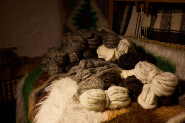 Wool in various colors is spread on a table in a craft space. This wool will be used for weaving. The scene shows a connection to local traditions and craftsmanship. © bondarillia