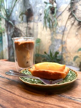 cup of coffee and lemon cake serve on green plate and fork, with caffee vibes background.