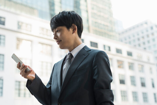 街中でスマートフォンを操作する20代男性ビジネスマン