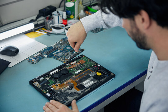 A man is working on a motherboard with a magnifying glass
