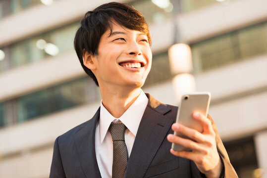 銀杏並木で電話する20代男性ビジネスマン
