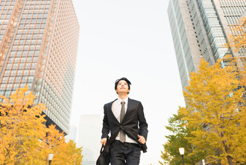 高層ビル街を走る20代男性ビジネスマン © One
