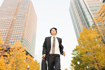 高層ビル街を走る20代男性ビジネスマン © One