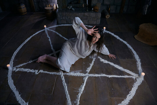 Kneeling woman conducts mystical summoning within circle