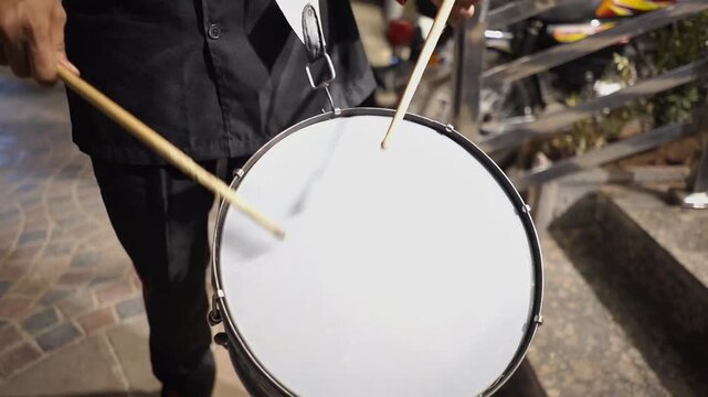 Close-up video of a marching band drummer playing a traditional drum during a wedding celebration. The footage captures live music performance, rhythmic drumming, festive atmosphere, cultural event