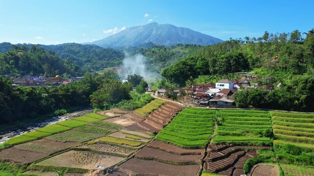 Aerial drone footage of Kawi volcano mountain, from Selorejo area, Ngantang area, Malang recency, Java island, Indonesia, with many agricultural fields, a wild river, rice fields and a village