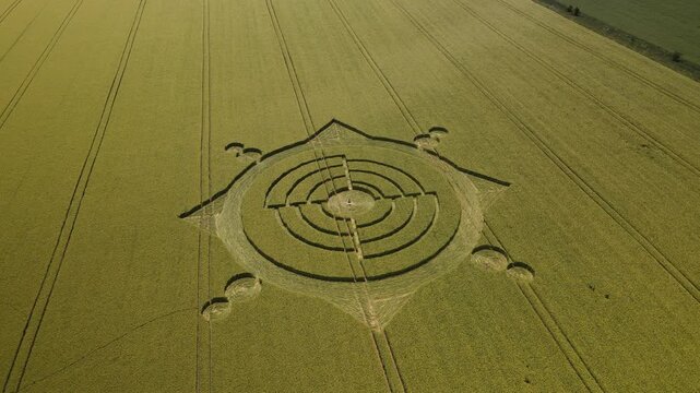 Aerial view of a geometric crop circle formation in a green field in Wiltshire, England, United Kingdom.