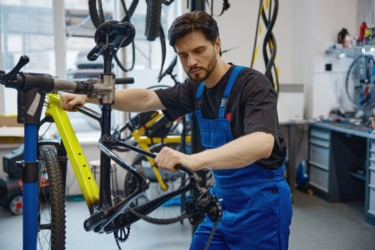 Skilled worker calibrating bicycle brake cable in workshop