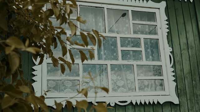 An authentic window of a rustic house with decoration, patterns and different symmetrical panes. Beautiful window of a wooden house. Ancient architecture.
