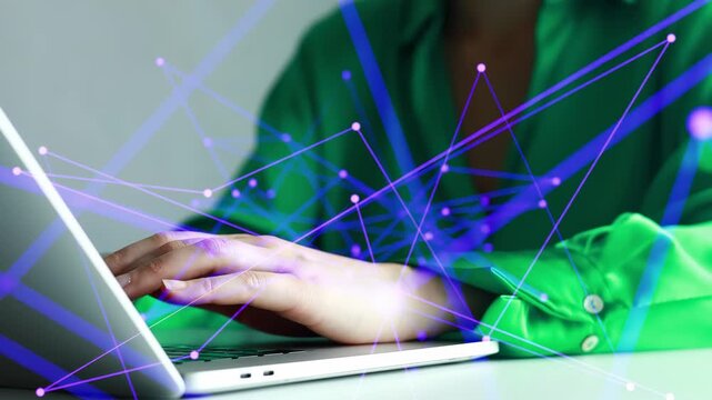 Working at a laptop with digital graphics showing connections and data at a simple workspace setting during the day.