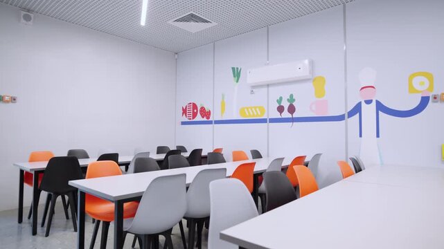 School canteen features neat rows of tables paired with vibrant chairs. Food-themed wall illustrations create cheerful dining atmosphere