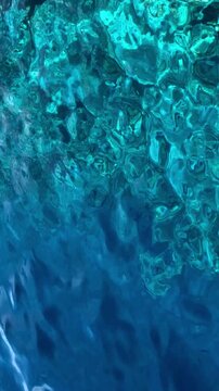 Clear blue water reveals a vibrant coral reef beneath the surface, showcasing marine life and underwater textures.
