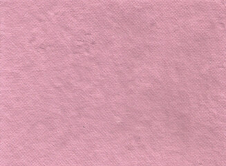 Fototapeta premium texture of thick handmade artisan paper in a soft dusty pink hue. The full-frame close-up captures a grainy surface with subtle fiber specks, dimples, and a vintage matte layout for elegant design wor