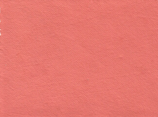 Fototapeta premium texture of handmade recycled paper in vibrant salmon pink. The solid color surface shows fine grain, elegant natural fiber patterns, and a matte appearance perfect for artistic scrapbooking.