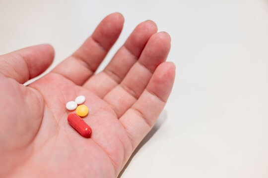 Medical pill capsule in hand for healthcare supplement concept with patient holding pharmacy medication and antibiotic drug tablet dose over clean white background.