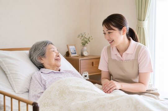 ベッドで寝ているシニア女性と寄り添う介護士