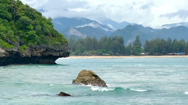 Scenic tropical coast landscape with green rocky cliff and misty mountains footage. Ideal for travel vlogs, nature documentaries, adventure tourism promotions, and cinematic b-roll transitions.