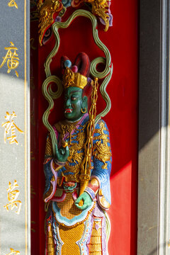Taipei, Taiwan - 15 January 2026: View of a colorful and ornate guardian deity statue carved into a temple wall, featuring intricate gold details and vibrant paint.