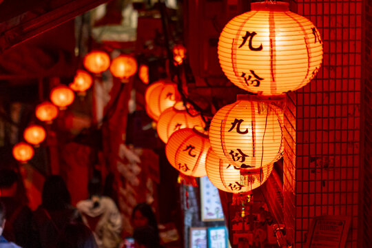 Taipei, New Taipei, Taiwan - 15 January 2026: View of glowing red lanterns hanging along a narrow, crowded street in historic Jiufen, with traditional architecture and warm evening light.
