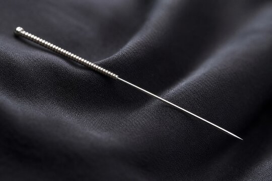 acupuncture. Slender silver acupuncture needle on dark silk fabric. STEM education sheets, lab safety posters, designed for STEM education and laboratory safety posters.