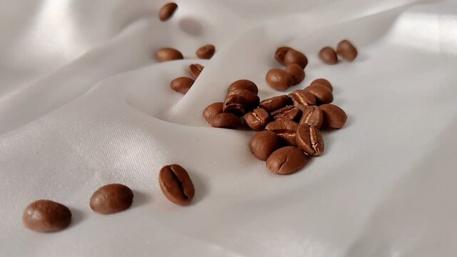 Roasted Coffee Beans Falling in Super Slow Motion on White Silk