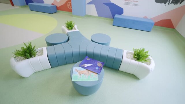 Modular seating with integrated planters stands on light green floor. Colorful wall murals enhance playful and inspiring atmosphere