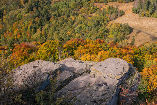 Aerial view of Sitno in Stiavnicke Vrchy featuring rugged rock formations overlooking a dense forest with vibrant autumn foliage in Ilija, Banska Bystrica Regio, Slovakia.