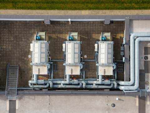 Aerial view of three industrial HVAC units on the rooftop of Factory Annopol with grey ventilation pipes and metal stairs in Warszawa, Mazowieckie, Poland.