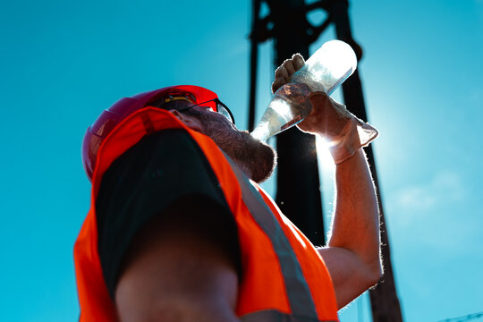 Bauarbeiter trinkt Wasser bei strahlender Sonne
