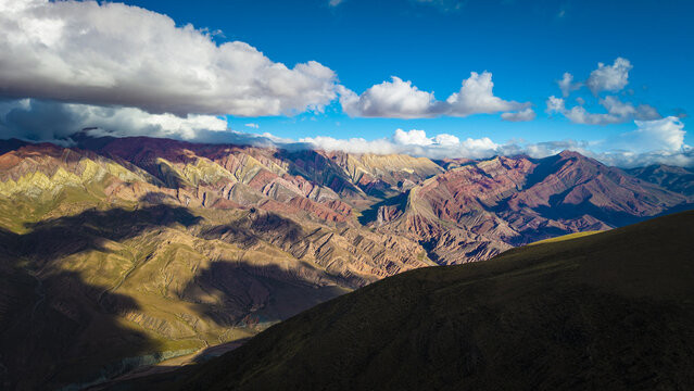 Aerial view of the colorful Serrania de Hornocal mountains with dramatic shadows and clouds in Humahuaca, Jujuy Province, Argentina.