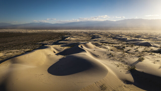 Aerial view of Dunas de Taton featuring vast sand dunes under a clear sky with distant mountains in Tinogasta Department, Catamarca Province, Argentina.