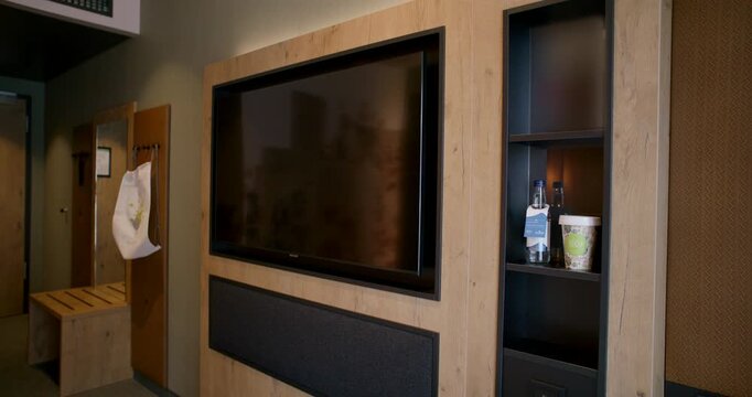 Modern hotel room interior showing a flat screen television mounted on a light wood wall panel