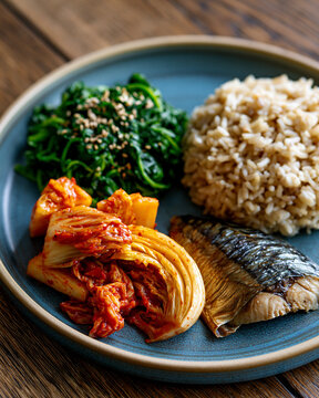 Minimal blue ceramic plate with kimchi mackerel spinach namul and brown rice showcasing Korean wellness longevity and anti inflammatory nutrition